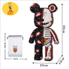 Niedliche Bärenfigur aus schwarz-weißen Bausteinen neben einer Box und einem Ameisen-Icon