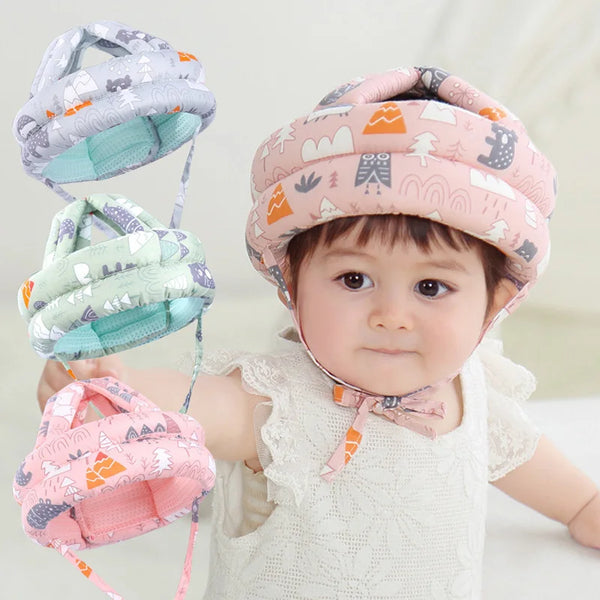 A baby is shown wearing a pink cartoon mesh safety helmet for toddlers with various colored mesh helmets nearby.