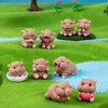 A collection of cute mini hippo resin figurines in various poses and colors placed on a green grassy surface.