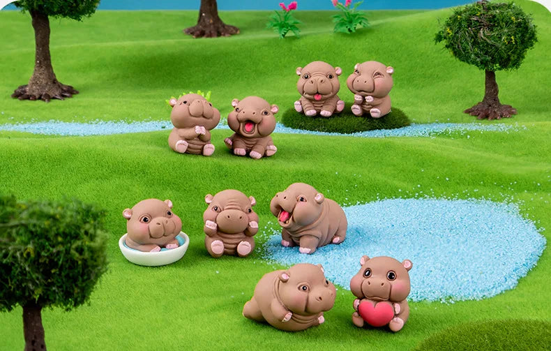 A collection of cute mini hippo resin figurines in various poses and colors placed on a green grassy surface.
