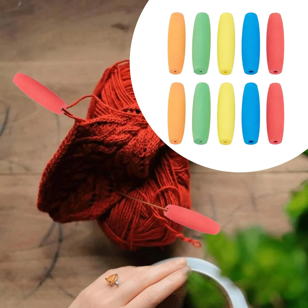 A hand holds a red knitted yarn ball with foam grip sleeves for tools and utensils displayed nearby.