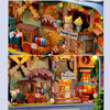 A wooden miniature dollhouse theater kit featuring a train and various furniture, set in an ornate scene.