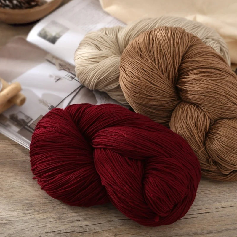 A close-up of thick red yarn is tightly wound and resting on a wooden surface.