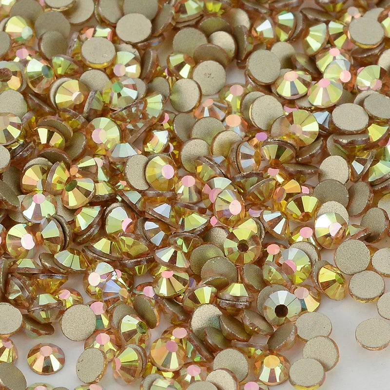 A close-up view of various flatback glass crystal rhinestones in gold and champagne tones.