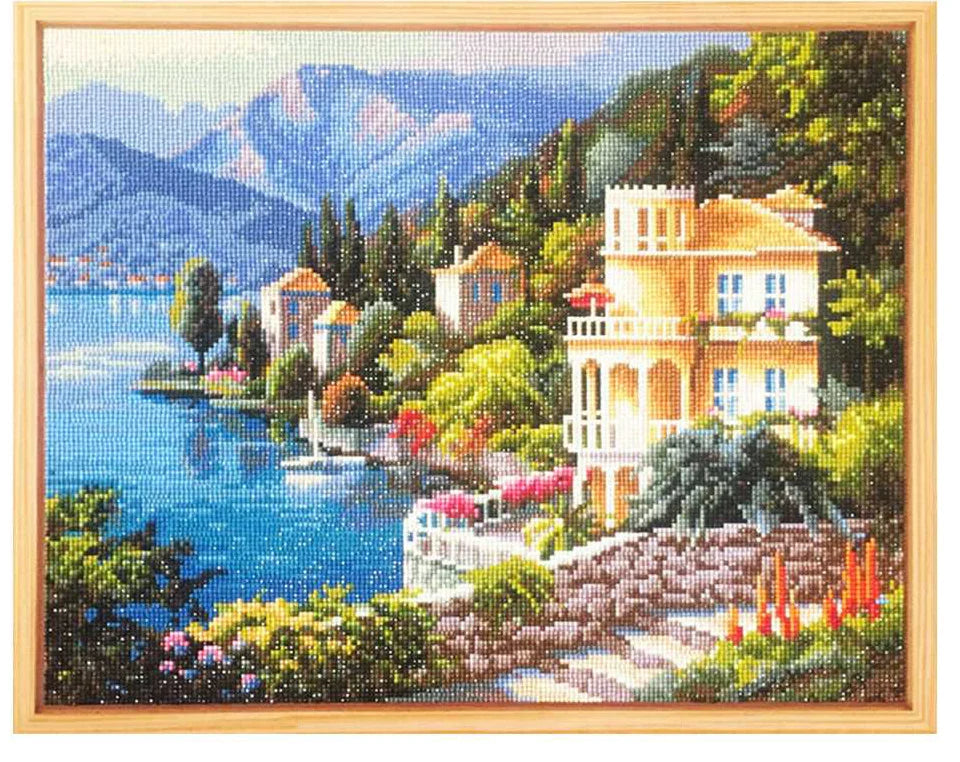 Diamond painting of a scenic landscape featuring a large house, mountains, and blue water.