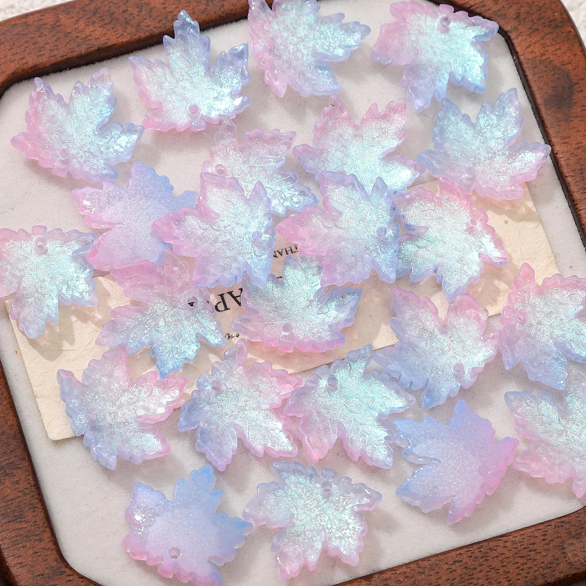 A collection of pink and blue maple leaf glass beads for DIY jewelry making