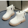 A pair of white faux leather winter boots with white fluffy trim and light tan soles displayed on a gray surface.