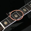 Close-up of acoustic guitar strings and a string changer tool on the fretboard.