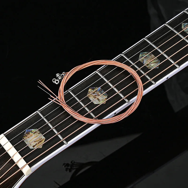 Close-up of acoustic guitar strings and a string changer tool on the fretboard.