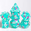 A set of handmade resin polyhedral dice featuring a teal color and pink floral designs.
