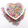 A white bowl filled with colorful polymer clay sprinkles for slime and craft decor, spilled around the base.