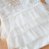 White lace baby romper with ruffled skirt and matching headband for a newborn photo outfit