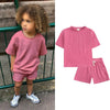 A pink kids summer tracksuit set featuring a short sleeve top and matching shorts displayed on a model.