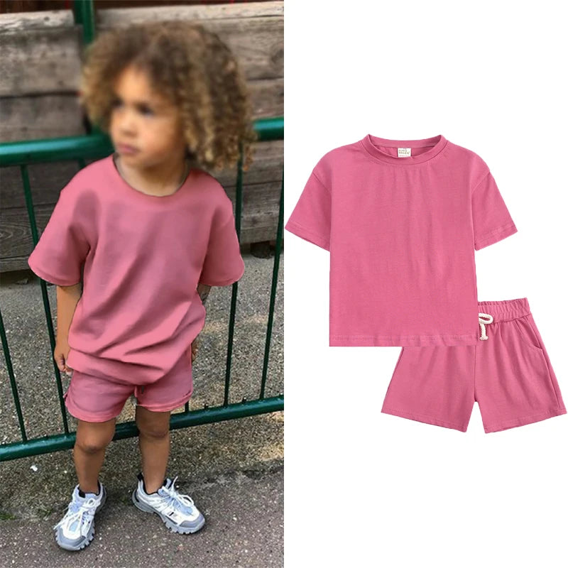 A pink kids summer tracksuit set featuring a short sleeve top and matching shorts displayed on a model.