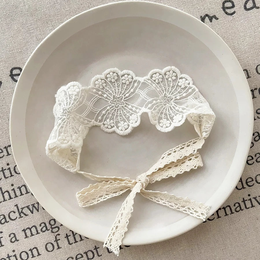 White floral lace baby headband displayed on a light background.