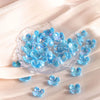A pile of small, translucent blue acrylic four-petal flower beads scattered on a light fabric.