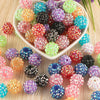 A collection of colorful rhinestone resin bayberry beads in various shades and sizes for jewelry making.