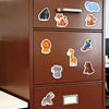 A close-up view of a brown cabinet with ten colorful animal fridge magnets attached to the door.