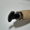 A close-up view of a professional bezel setting pusher tool with a dark metal tip and a light wooden handle.