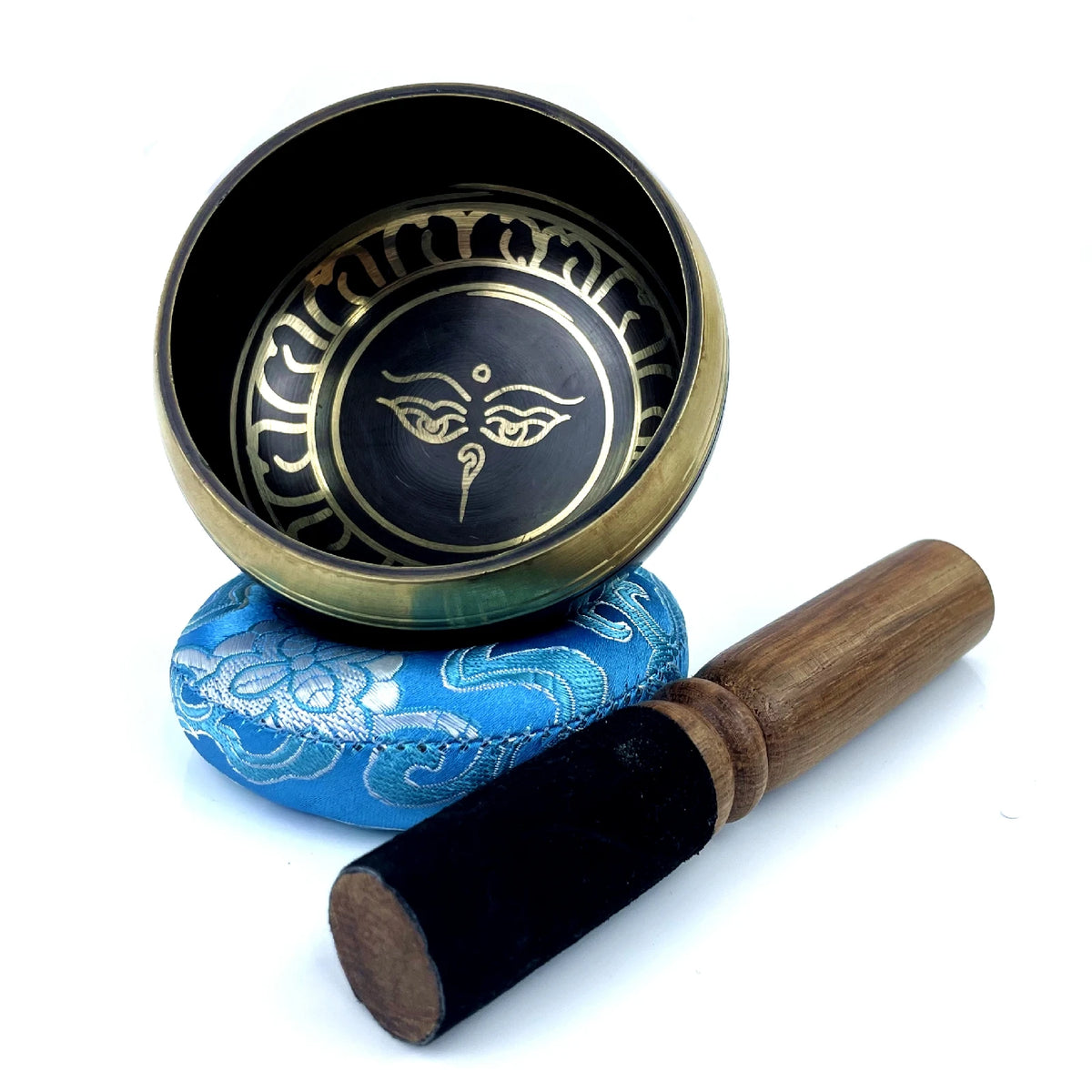 Handcrafted Tibetan singing bowl with a silk cushion and wooden mallet resting on a white background.