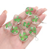 A hand holds a set of handmade glass four leaf clover pendants for jewelry making