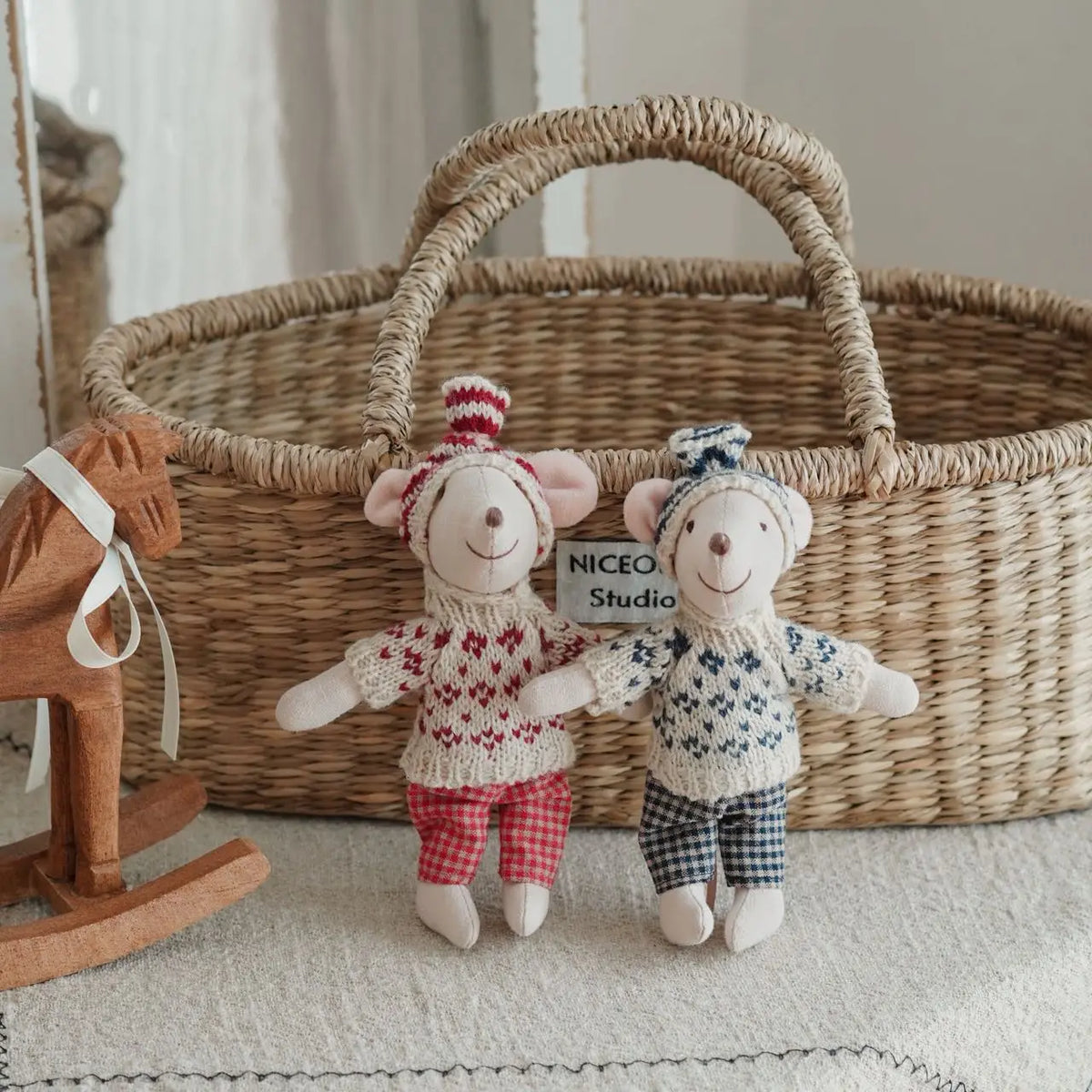 Two handmade mouse plush dolls wearing retro outfits sitting in a woven basket