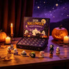 A Halloween advent calendar box with a spooky theme and 24 resin ornaments displayed on a wooden table.