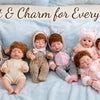 A collection of twelve 12-inch reborn dolls dressed in cozy winter outfits lying on a blue blanket.
