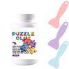 A bottle of clear puzzle preserving glue with pink and purple plastic spoons shown next to it.