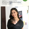 A woman is holding a baby in a black X-shaped baby sling carrier.