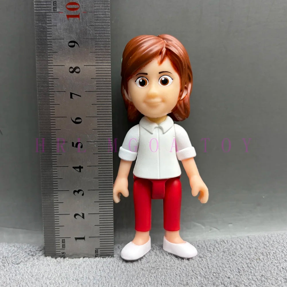 A figurine of a girl with reddish hair wearing a white shirt and red pants, standing next to a ruler.