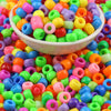 A close-up shot of a bowl filled with brightly colored, solid color pony beads for jewelry making and craft projects.