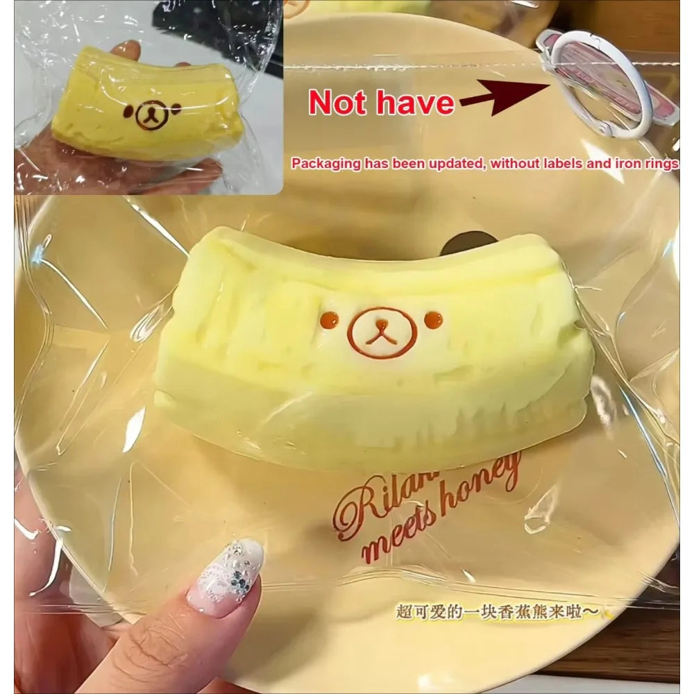 A yellow banana bear squishy stress relief toy is shown on a clear plastic tray.