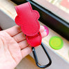 A hand holds a red PU leather stroller organizer hook with a black clip against a light background.