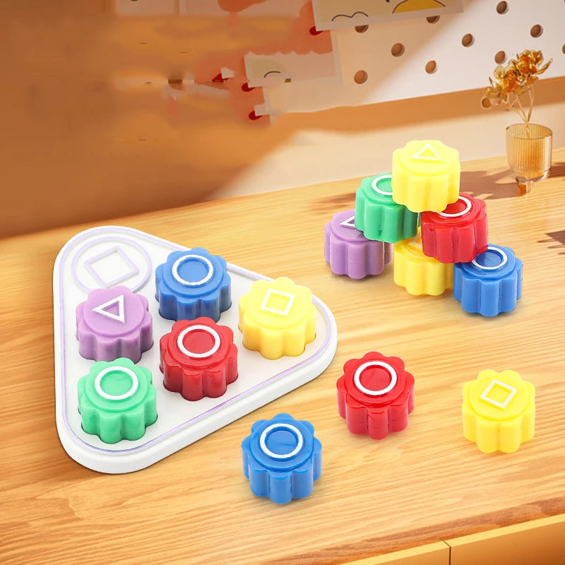 A set of five colorful gonggi stones in various shades of green, yellow, pink, and blue arranged on a wooden surface.