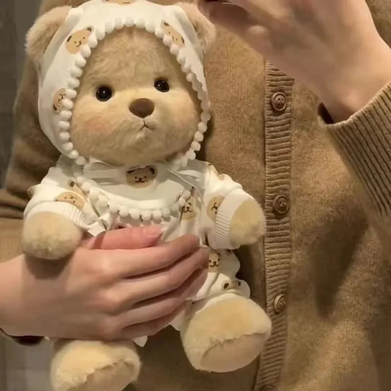 A fluffy teddy bear plush wearing a white dress with pearl trim being held by a person.