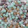 Mixed color faceted rondelle glass beads in shades of green, purple, and beige for jewelry making