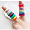 A hand displays a stack of colorful nylon hair ties in various shades of pink, purple, green, and yellow.