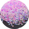 A pile of iridescent pink and purple glass rice beads for DIY jewelry and crafting.