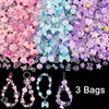 A mix of pink, purple, and blue acrylic beads for DIY jewelry making, displayed in three bags.