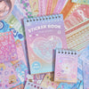 A stack of pastel-colored sticker books and sheets featuring various decorative patterns and designs for crafting.