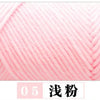 A close-up of pink milk cotton yarn being wound on a knitting machine.