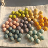 A collection of colorful, smooth, spherical sensory music trees with marble run components arranged on a white cloth.