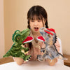 Une jeune fille tient un marionnettiste dinosaure en peluche aux écailles vertes et grises.
