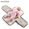 A newborn baby lying on a portable changing mat with a storage bag.