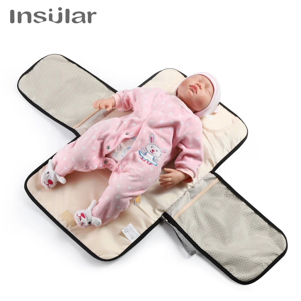 A newborn baby lying on a portable changing mat with a storage bag.