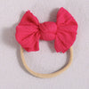 A bright pink fabric bow headband with a light beige elastic band, displayed on a white background.