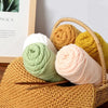 A collection of soft colored yarn balls in various shades of yellow, green, and pink are displayed in a woven basket.