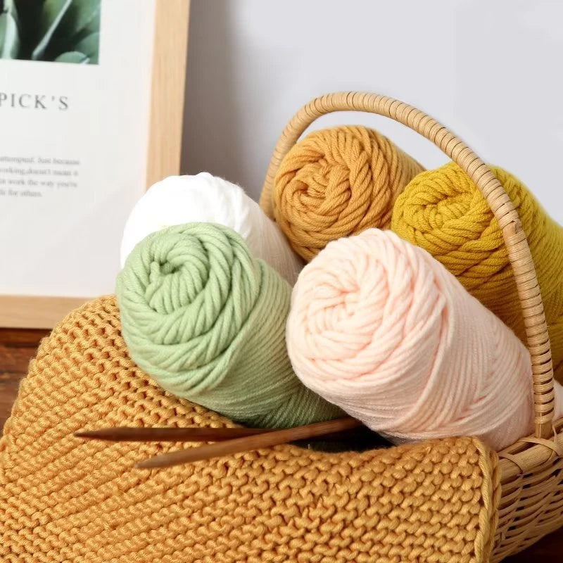 A collection of soft colored yarn balls in various shades of yellow, green, and pink are displayed in a woven basket.