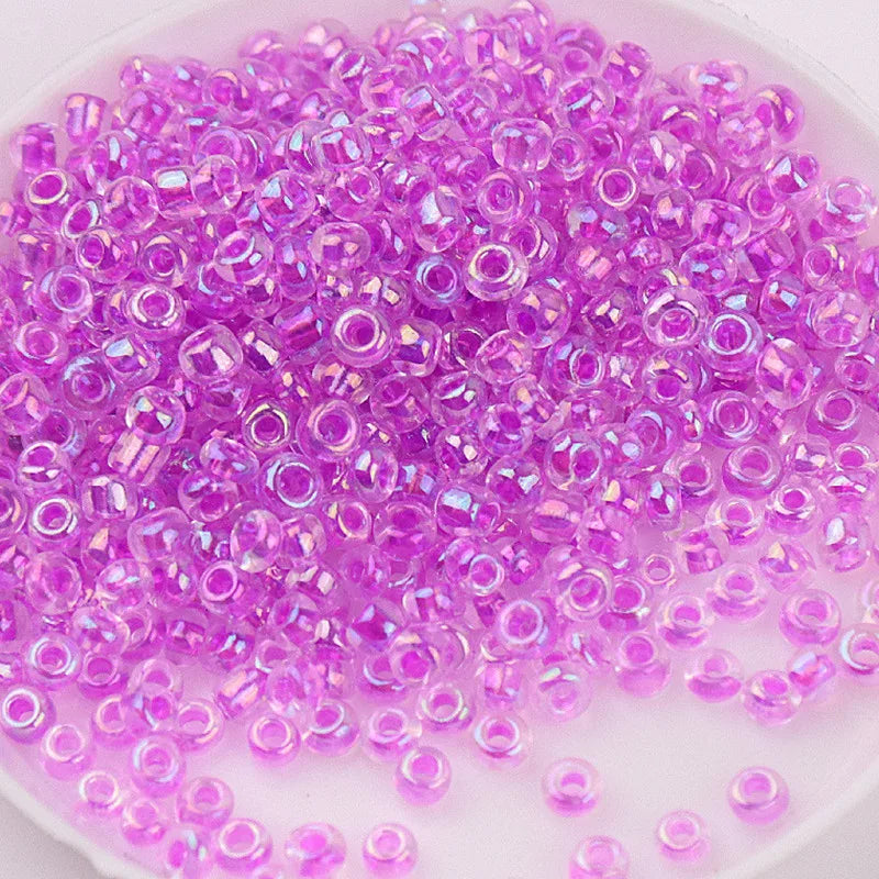 A pile of small, translucent purple glass rice beads for DIY jewelry and crafting.